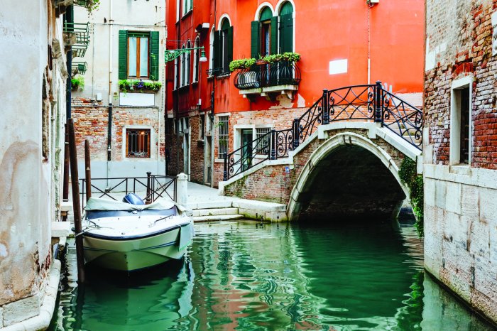 Fototapete Blick auf die Brücke und ein Boot zwischen den Häusern