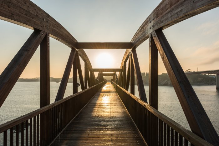 Fototapete Holzbrücke über dem Fluss im Sonnenlicht