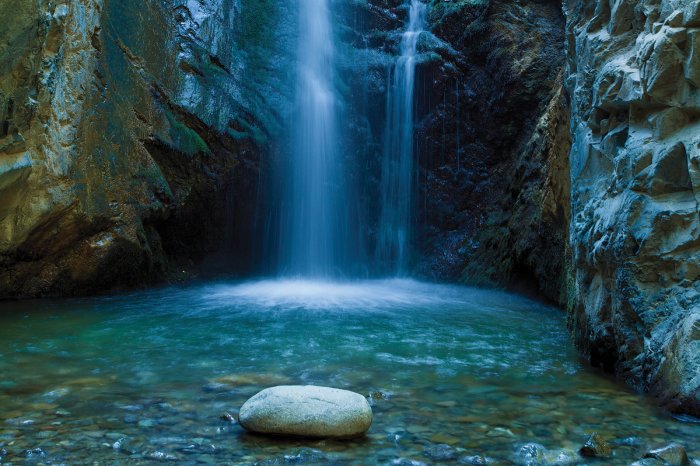 Fototapete Höhle mit einem Wasserfall und Felsen