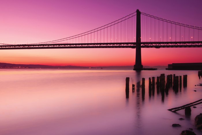 Fototapete Landschaft mit Sonnenuntergang und einer Brücke vor rosa Himmel