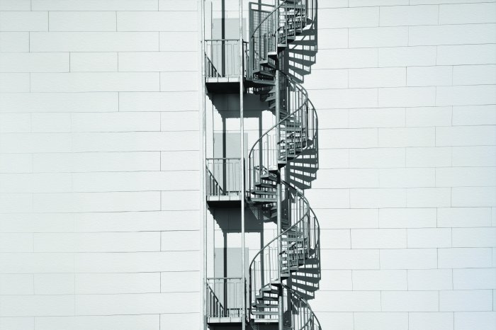 Fototapete Wendeltreppe an einer weißen Backsteinwand