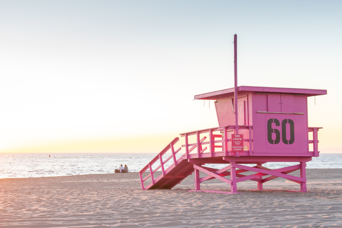 Bild Ein pastellfarbener Rettungsschwimmerstand mit Blick auf den Ozean bei Sonnenaufgang
