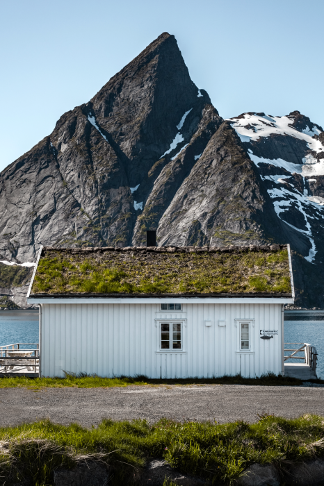 Poster Ein weißes Haus mit Bergen im Hintergrund