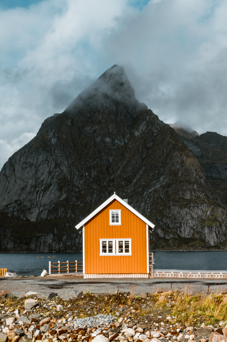 Poster Ein orangefarbenes Haus inmitten der Berge und des Meeres