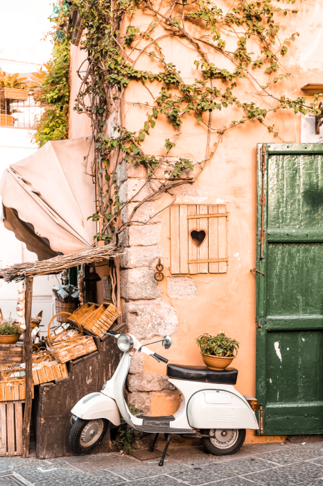 Poster Ein weißer Roller vor einem mit Weinreben bewachsenen Gebäude im Hintergrund