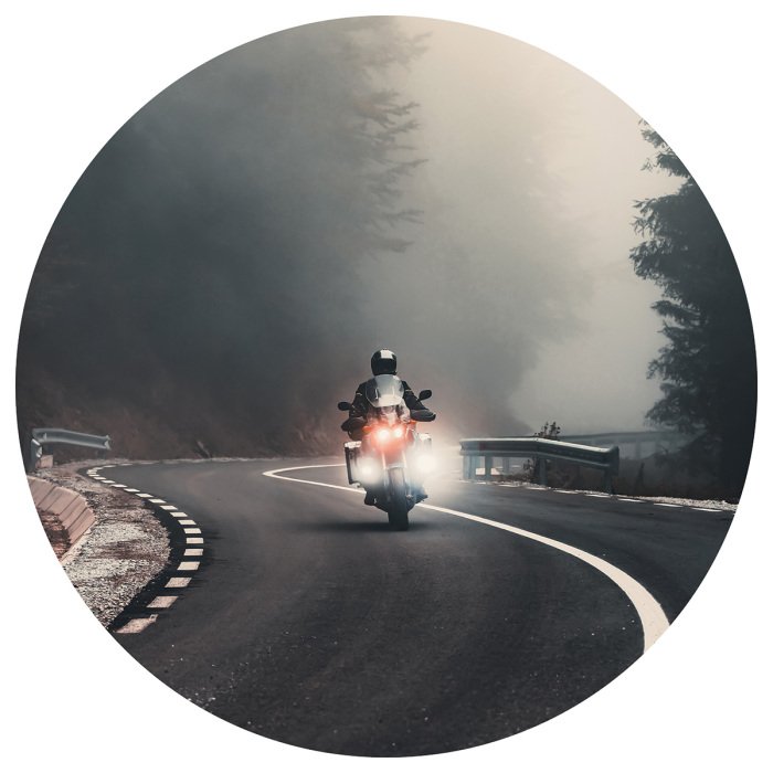 Sticker Ein Motorradfahrer auf einer Straße vor nebliger Landschaft