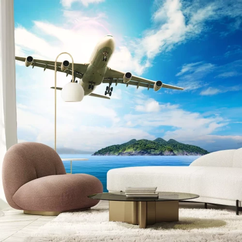 Fototapete Ein Flugzeug im Flug über einem blauen Meer und einer Insel