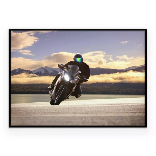 Poster Ein Motorradfahrer fährt vor der Kulisse von Bergen und Wolken.