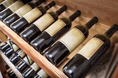 Fototapete Weinflaschen auf Holzregal platziert